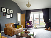 Zweisitzer-Sofa mit Kunstwerk in einem Wohnzimmer in Manchester mit lila Vorhängen, England, UK