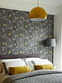 Grey and yellow bedroom with bird and leaf patterned wallpaper in Manchester home, England, UK