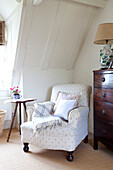 Weißer Sessel mit Blumenmuster und antike Kommode aus poliertem Holz in einem Fachwerkhaus in Kent, England, UK