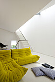 Yellow seating in white open plan contemporary London apartment, England, UK