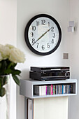 Stereo and music collection on wall storage below clock in contemporary London home, England, UK