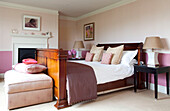 Antikes poliertes Holzbett im rosa Schlafzimmer eines Hauses in Kent, England, UK