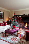 Christmas gifts and drinks on ottoman footstool with festive decoration in Kent home, England, UK