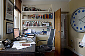 Desk and chair with computer in artists studio with pots of paint