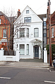 White painted London townhouse and driveway from road, UK