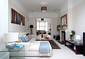 Light blue blanket on white sofa below modern art in double room of contemporary London home, UK