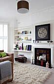 Ornaments on shelving next to fireplace in white living room of contemporary London home, UK