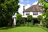 Lawned back garden exterior of conservatory extension, London semi-detached house, England, UK