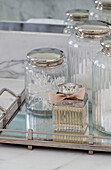 Vorratsgläser und Parfümflasche auf Silbertablett in einem Haus in Hendon, London, UK