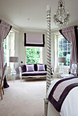 Purple and lilac upholstery with two seater sofa in window of master bedroom in classic home