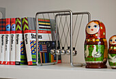 Schreibtisch mit Spielzeug und Büchern mit russischen Puppen auf einem Regal in einem Londoner Interieur UK