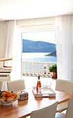 Bowl of oranges and rose wine on dining table in room with a view of the mediterranean sea in holiday villa, Republic of Turkey