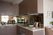 Brown fitted retro fitted kitchen in open plan apartment with mirrored splashback