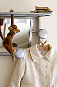 Hölzerner Affe und Mantel hängen an einem silbernen Regal in einem Londoner Haus UK