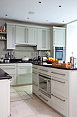 White fitted kitchen units and hob with utensil rack in contemporary London townhouse, UK