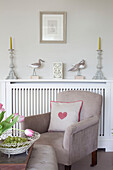 Heart shaped cushion on armchair at radiator in Sussex home UK