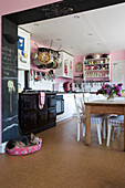 Dog sleeping in pink Suffolk kitchen with chalkboard and range oven UK