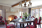 Pink embroidered chairs in dining room with lit fire Cotswolds UK