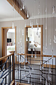 Glass droplet mobile hangs in stairway of Cotswold home UK
