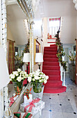 red carpeted staircase in white entrance hall with Christmas decorations in London home, UK