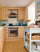 Light wood and pale blue fitted kitchen with glass fruit bowl and presents