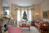 Beleuchtete Kerzen und Weihnachtsbaum und Geschenke im Wohnzimmer eines Londoner Hauses, UK