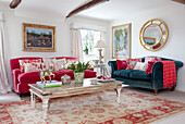 Contrasting sofas with coffee table on patterned rug in living room of Sussex farmhouse, UK