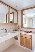 Wood framed mirrors and bathroom cabinet above double basin in contemporary London home, UK