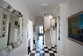 Checked floor tiles in hallway with mirror and artwork in London home UK