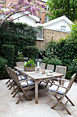 Patio table and chairs in courtyard garden of contemporary London townhouse, England, UK