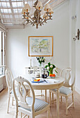 White painted table for four below ceiling light in conservatory extension of contemporary London townhouse, England, UK