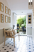 Open back door from tiled hallway with art display and bench seat in classic Tyne & Wear home, England, UK