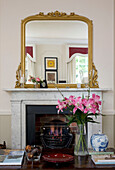 Geschnittene Lilien auf dem Couchtisch mit vergoldetem Spiegel auf dem Kaminsims in einem klassischen Haus in Tyne & Wear, England, Vereinigtes Königreich