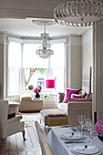 Weißes und rosafarbenes Mobiliar in einem offenen Wohn- und Esszimmer in einer modernen Londoner Wohnung, UK
