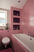 Pink tiled bathroom in retro styled East Sussex home, England, UK
