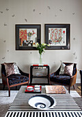 Passende Sessel und Kunstwerke im Wohnzimmer mit schwarz-weiß gestreiften Couchtischen in einem modernen Londoner Stadthaus, England, Vereinigtes Königreich