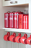Red storage tins and cups in recessed shelving alcove in London townhouse, England, UK