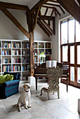 Dog sits in timber framed piano room with bookshelf Sussex UK
