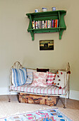 Two seater daybed below wall mounted bookcase in Kent farmhouse England UK