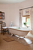 Pink spotted roll top bath at window of Kent farmhouse England UK