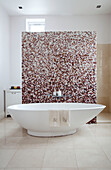 Freestanding bath with mosaic tiled partition in contemporary bathroom of London home, UK