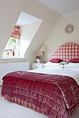 Gingham checked headboard on double bed in attic room of Kent cottage, England, UK