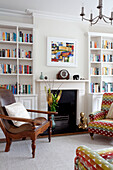 Modern art above fireplaces with bookcase and antique chair in Herefordshire family home England UK