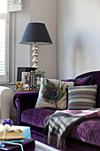 Peacock feather and stripey cushion on purple sofa in contemporary London home, UK