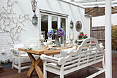 White painted bench seats on wooden patio exterior of London home, UK
