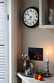Lit candles and utensils with wall mounted clock in London home, England, UK