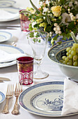 Glassware and bowl of fruit with centrepiece at place setting on dining table in Sussex farmhouse, England, UK
