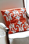 Orange applique cushion on armchair in London townhouse, England, UK