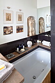 Goldstatue und Kunstwerk mit Toilettenartikeln auf einer Badewannenverkleidung in einem Londoner Stadthaus, England, UK