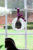 Glass bauble at window of Surrey farmhouse with orchid and horse statue, England, UK